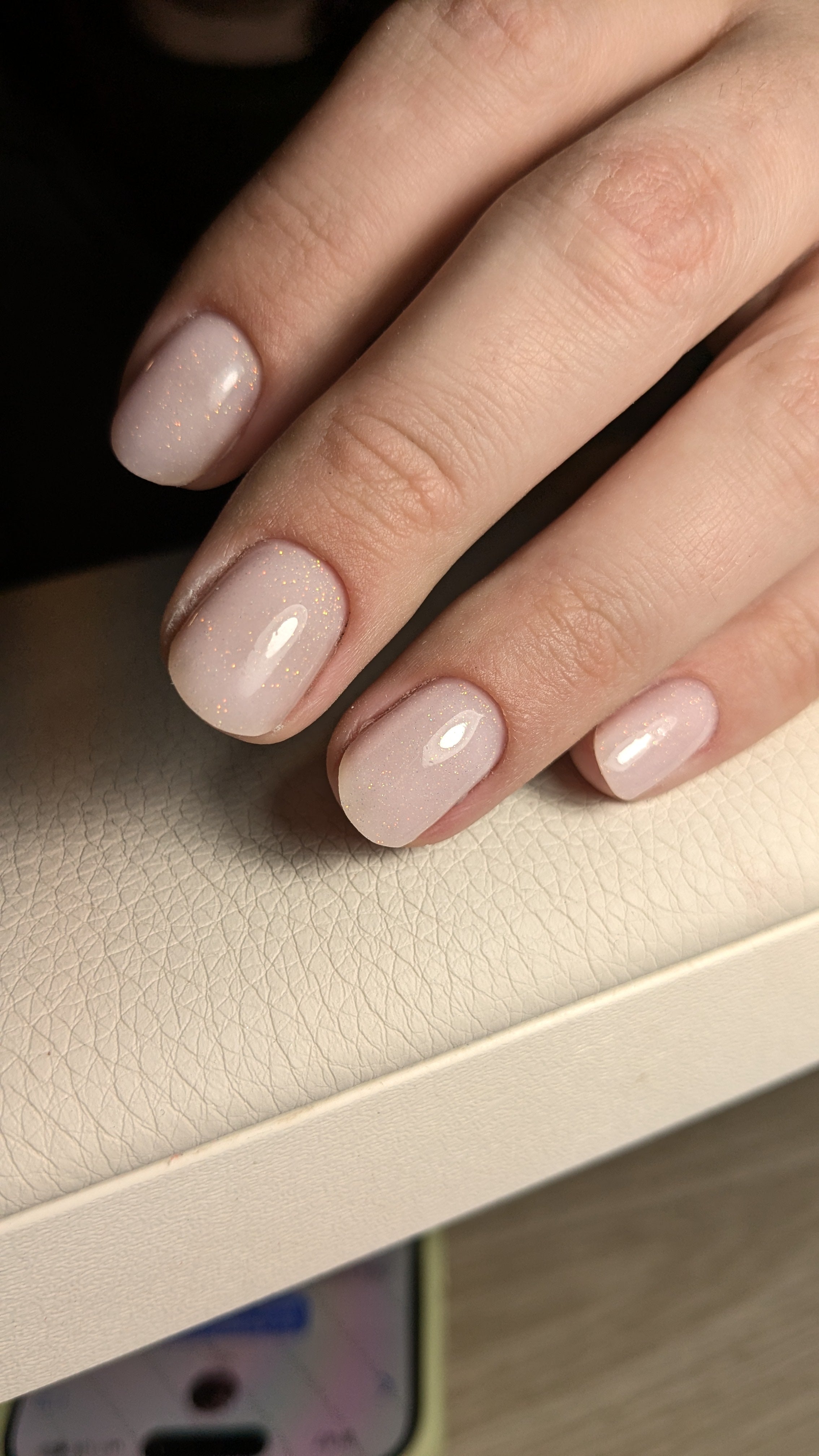 Closeup of sparkly cream colored gel polish nails.