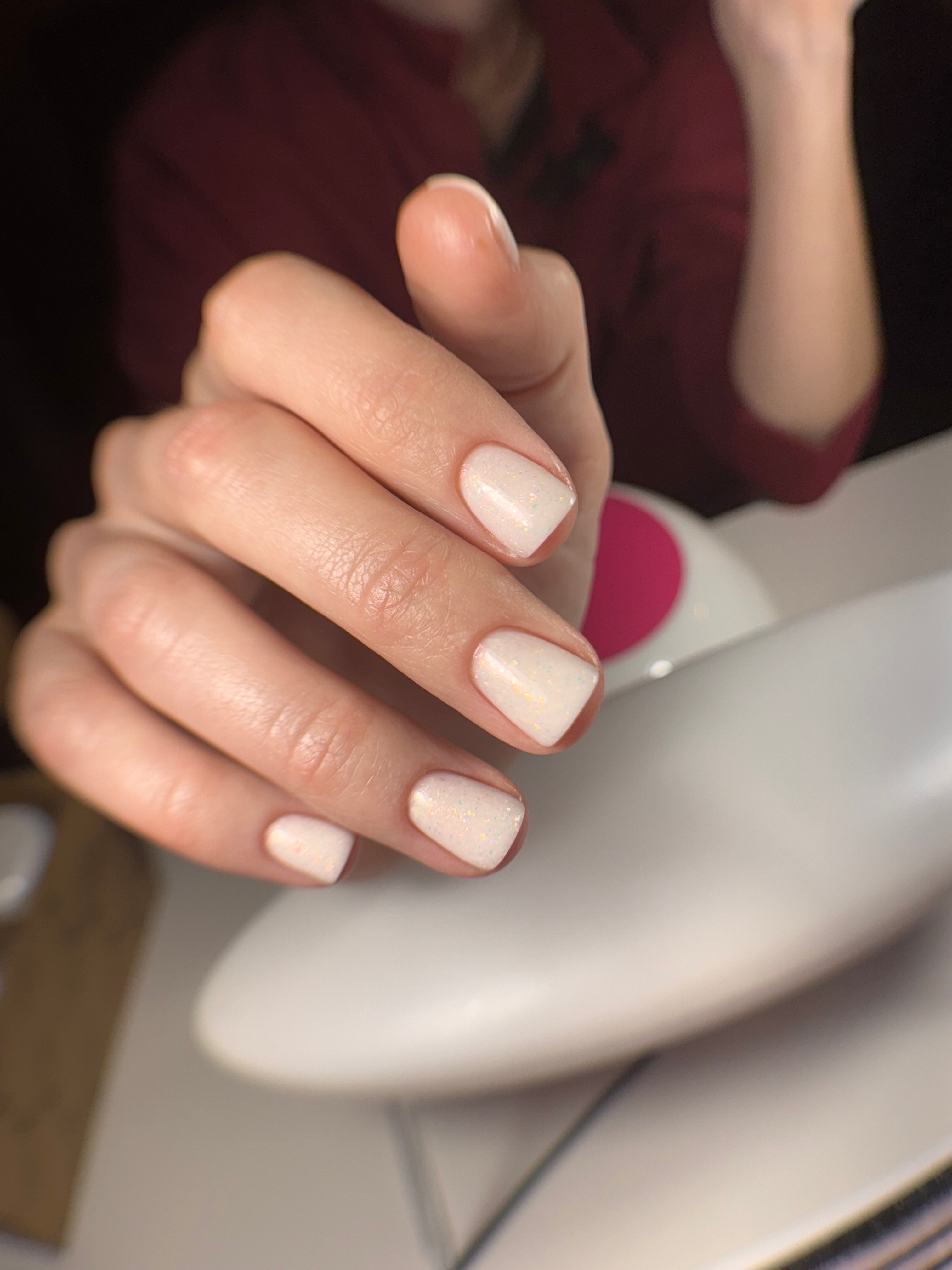 Closeup of off-white sparkly gel polish nails
